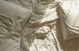 white wrinked sheets and pillow on bed